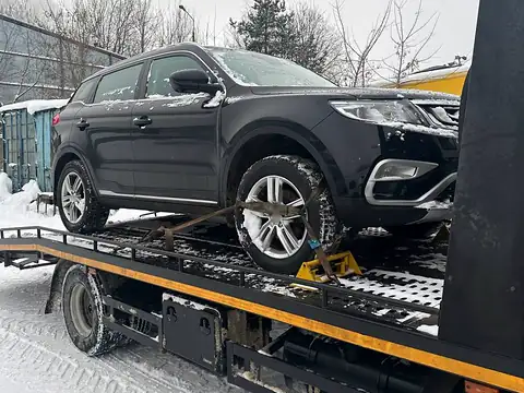 Автомобиль на платформе эвакуатора зимой: колесо закреплено ремнём, вокруг снег