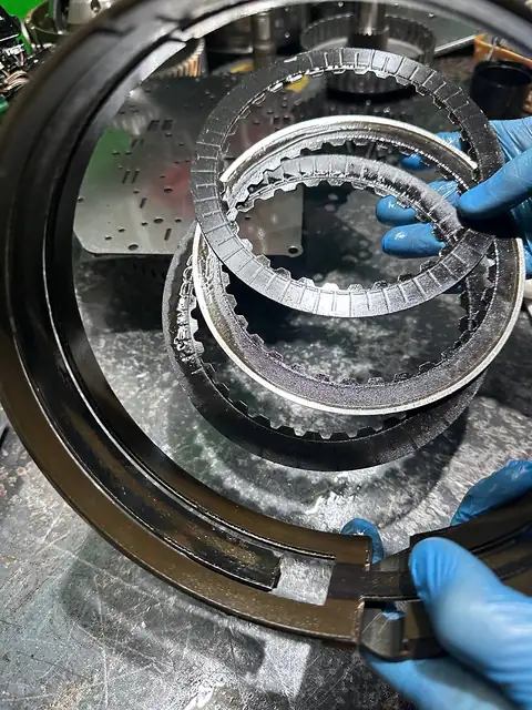 Фрикционные диски АКПП со стёртыми накладками в руках в перчатках