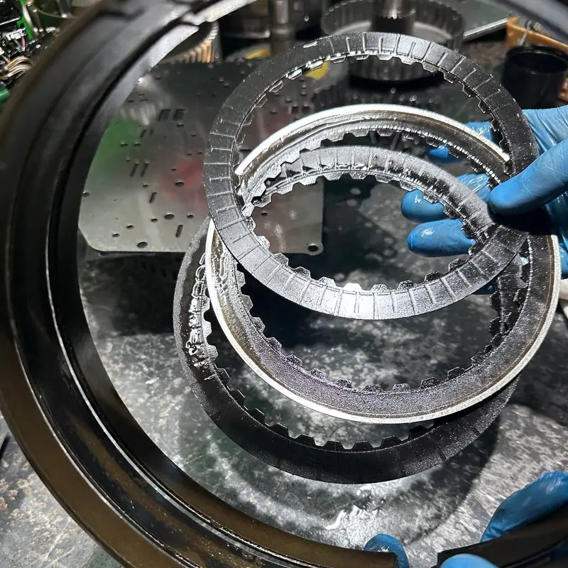 Изношенные фрикционные диски коробки-автомата в руках мастера в перчатках: накладки стёрты